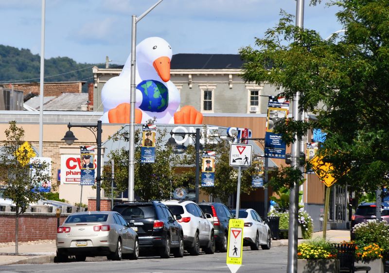 A giant inflatable goose holding a globe on the roof of the One-Stop office, seen down Market Street in downtown Lewistown with Lewistown Honors banners on the light poles