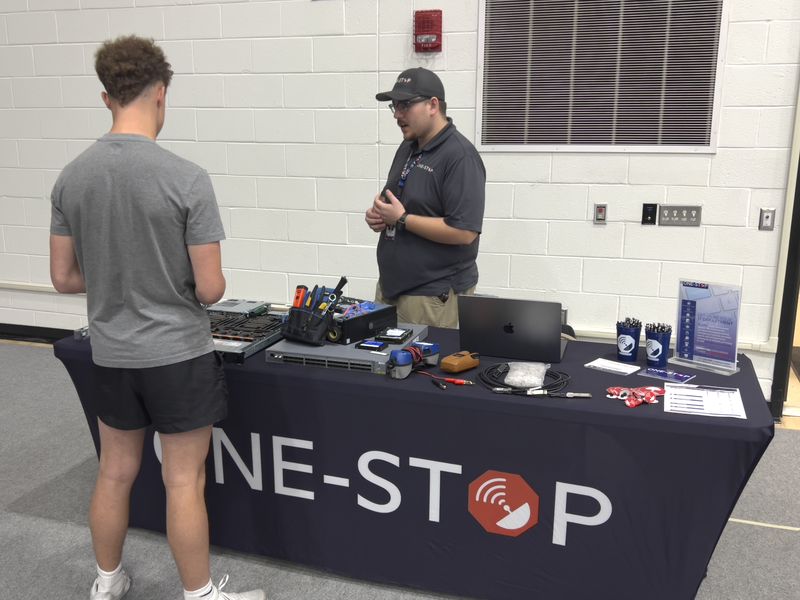 A One-Stop team member talking with a high school student at the One-Stop Career Day table
