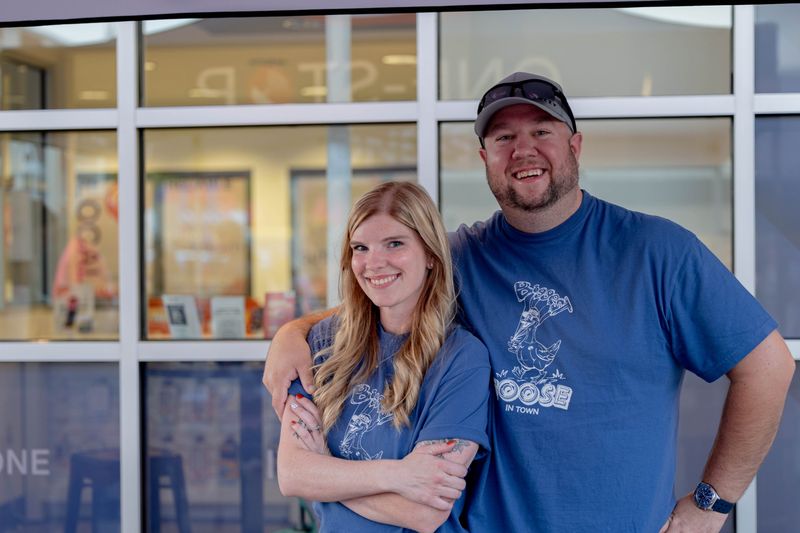 Two One-Stop team members in Goose Day shirts smiling outside the One-Stop office in downtown Lewistown